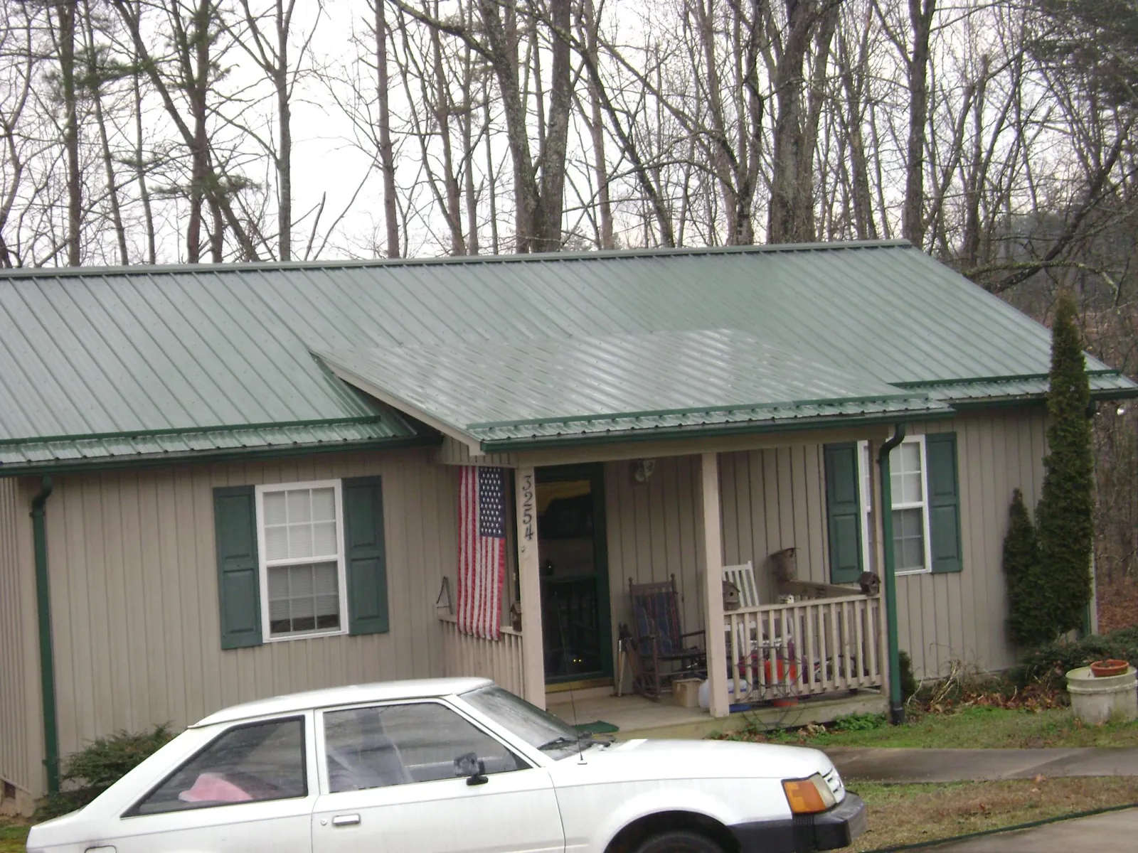 Green metal roof and front porch on a tan sided cottage in El Dorado
