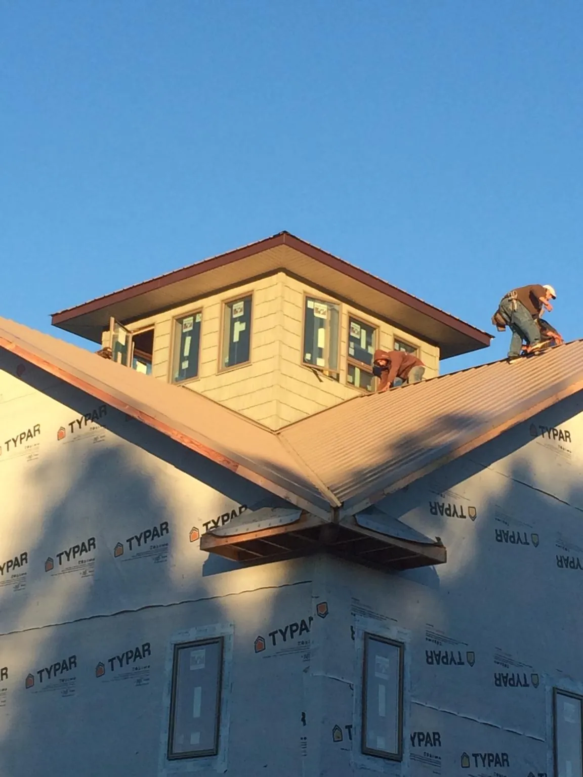 Roofers working around a rooftop cupola on a new metal roof at sunset — Roof Waterproofing in El Dorado by Roofing Brothers